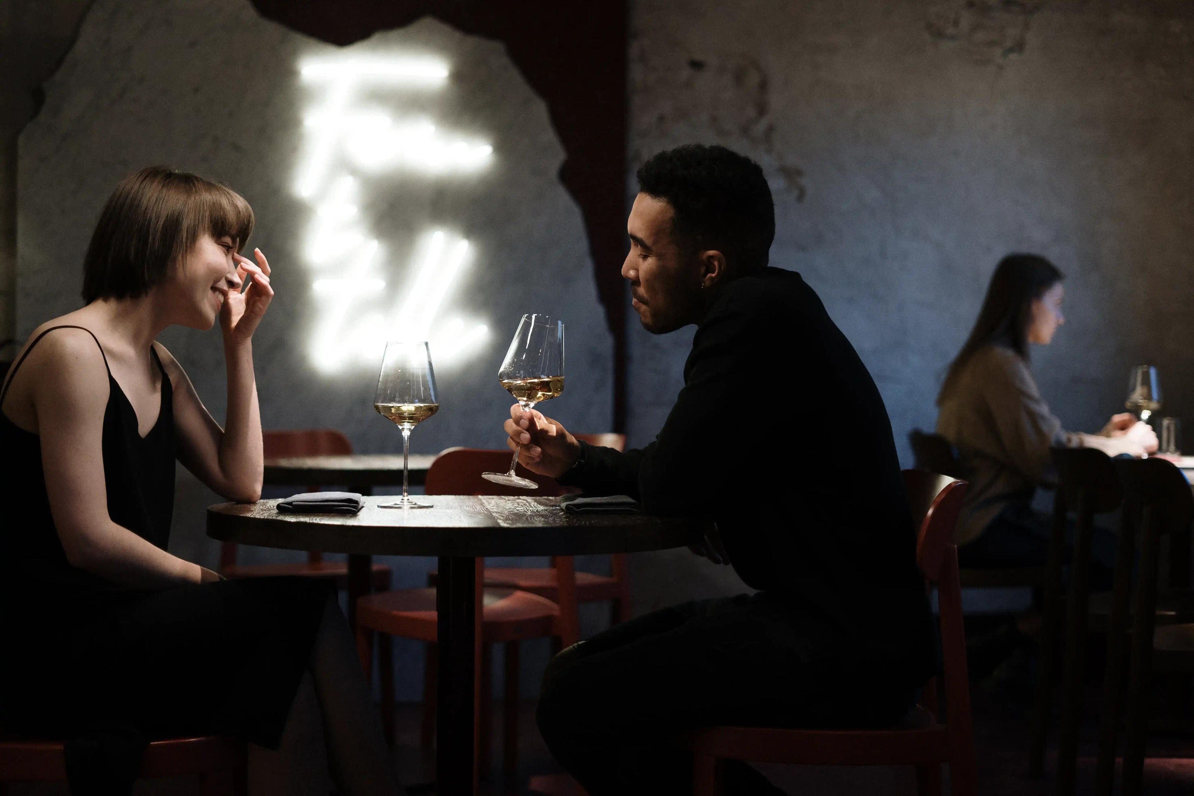 Two People sitting at a table in a restaurant, drinking wine.